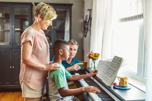 Woman in White Tank Top Holding Boy in Blue Polo Shirt Playing Piano