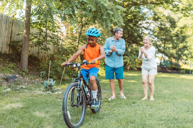 A Happy Couple Cheering For Their Son Riding A Bike 