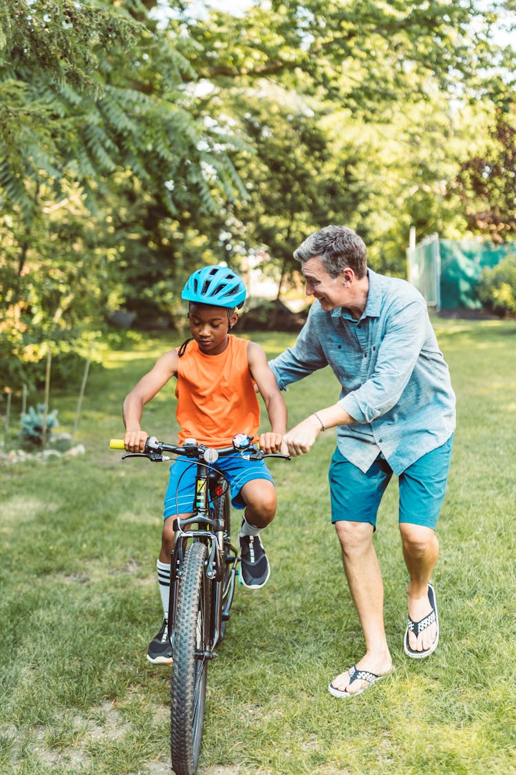 Man Assisting A Boy To Ride A Bicycle