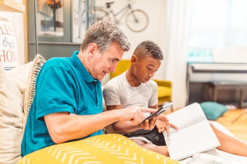 Father and Son Sitting on a Couch while Studying Lesson