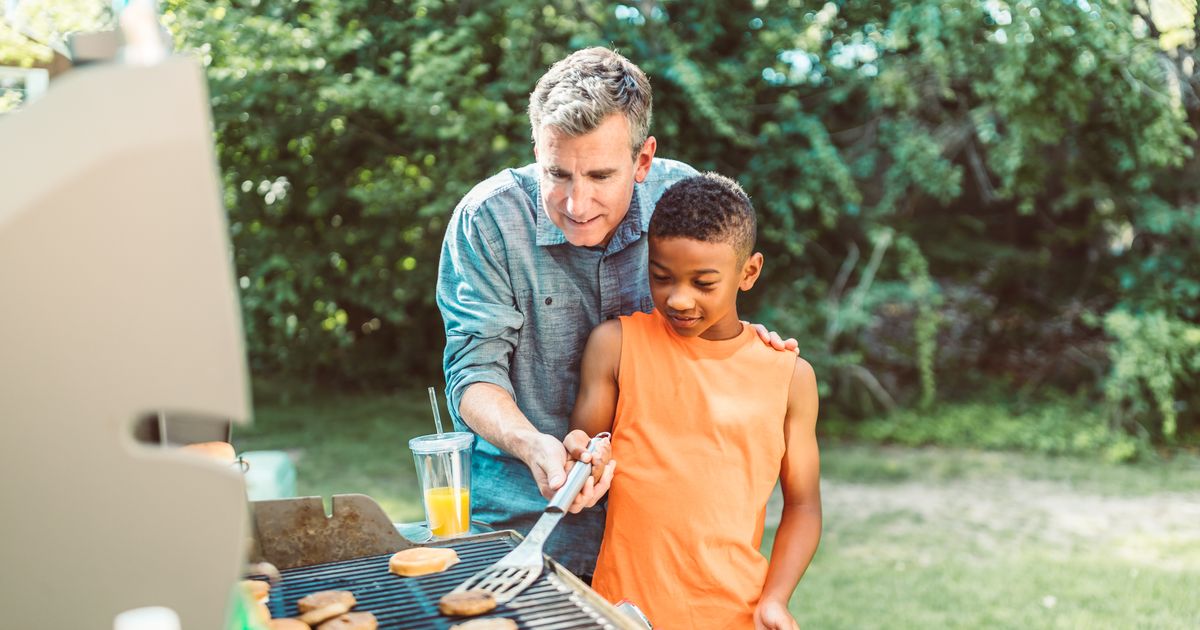 A father and son grilling together outdoors on a sunny day