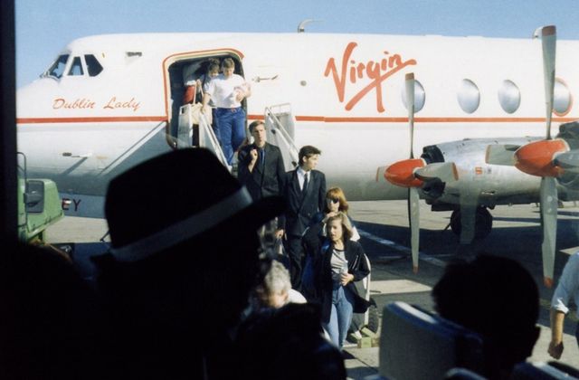 Passengers exiting a Virgin aircraft titled 'Dublin Lady' at Dublin Airport on a clear day. — arriving in Dublin