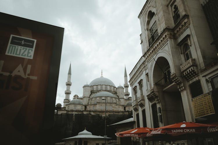 A Blue Mosque Beside A Building With Patio Umbrellas