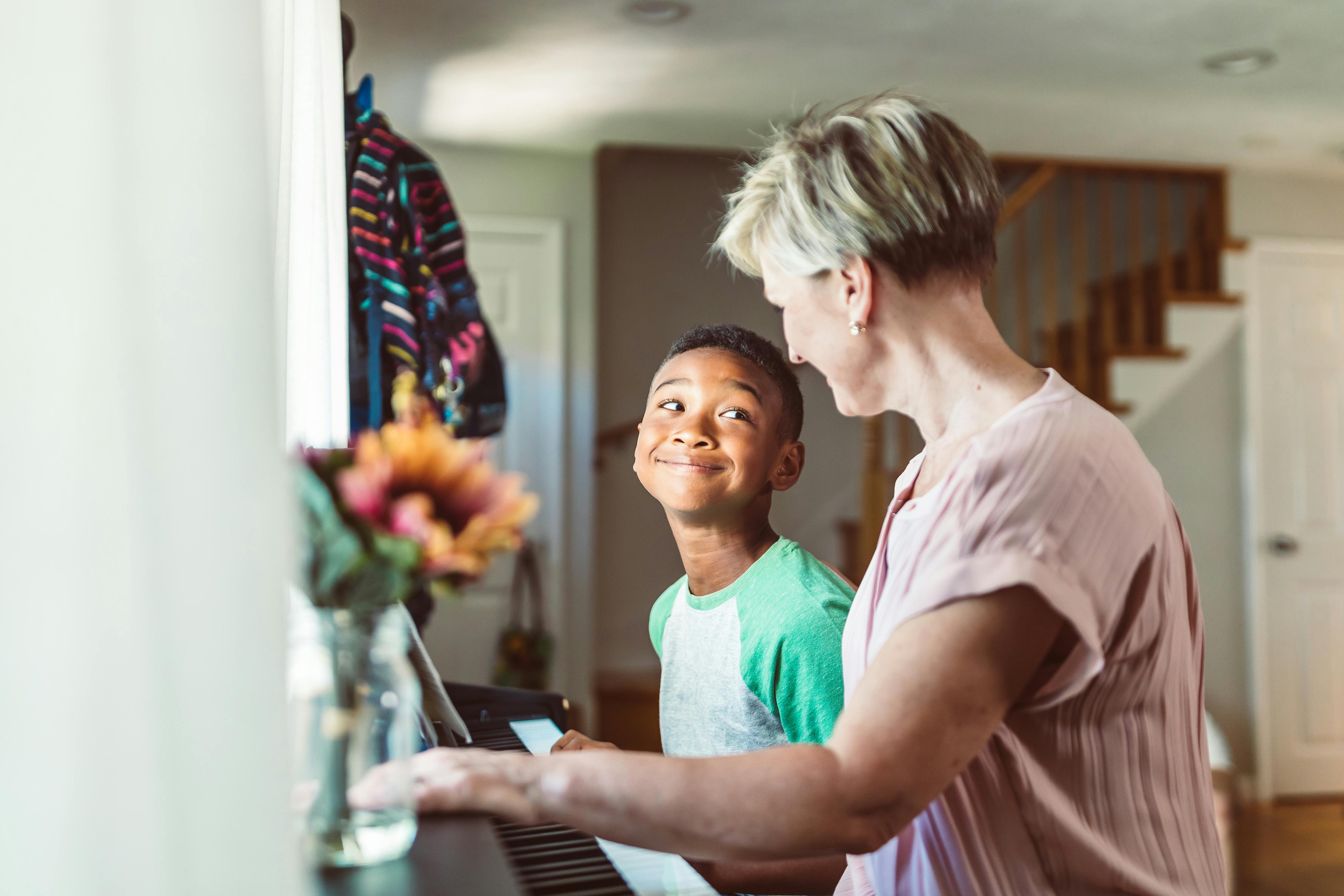 a boy playing piano beside a woman