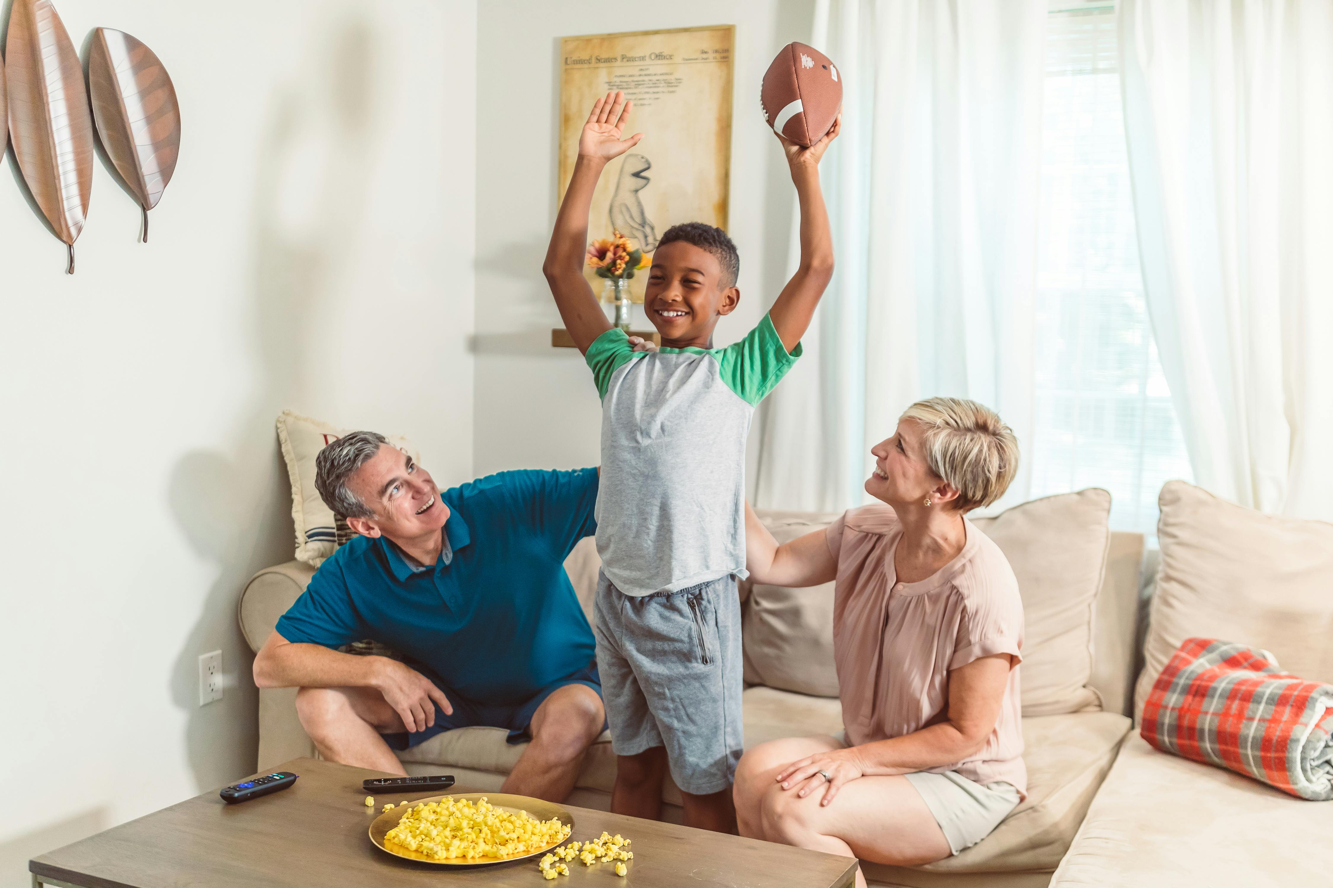 boy in white and green shirt holding brown football