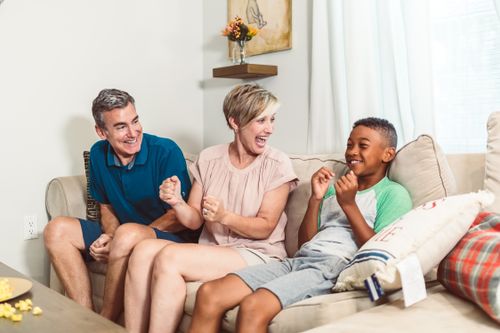 Free A cheerful family with a son enjoying quality time together on the living room couch. Stock Photo