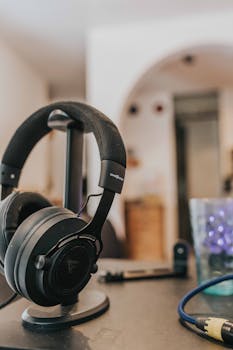 Close-up of sleek headphones on a stand indoors, showcasing modern audio technology.