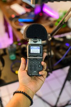 Close-up of audio recorder being held in a modern studio setting.