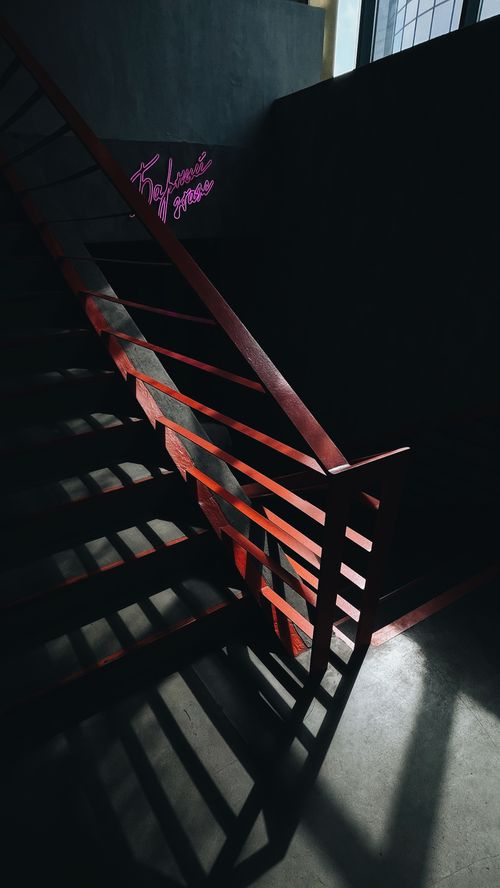 Free Dramatic staircase with shadows and neon signs, captured indoors in low light. Stock Photo