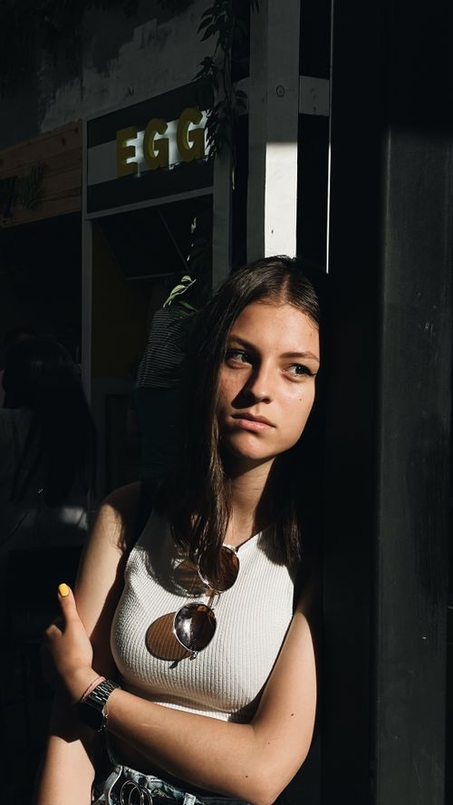 Free A young woman is posing thoughtfully in an urban environment with strong shadows, creating a dramatic mood. Stock Photo