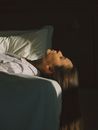 Woman in White and Blue Shirt Lying on Bed