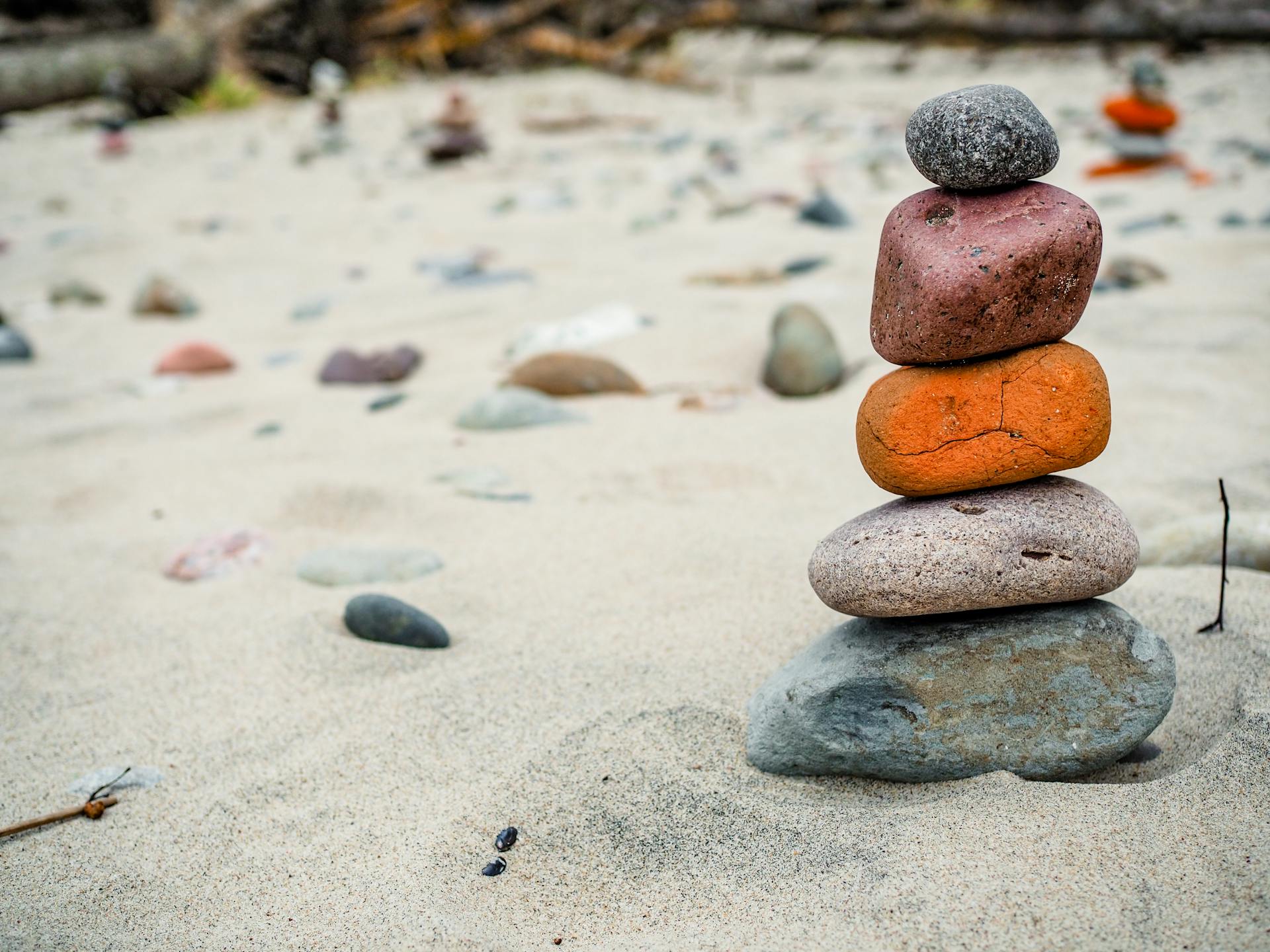 A close-up of stacked rocks on a sandy beach, emphasizing balance and harmony.