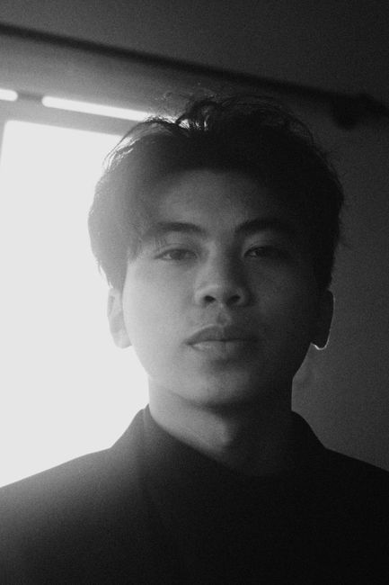 Artistic black and white portrait of a young man with soft lighting and moody expression.
