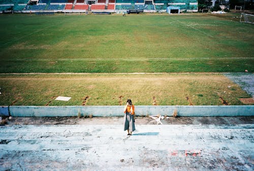 Woman in Black Dress Walking on Green Grass Field