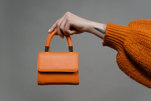 Person Holding Orange Leather Shoulder Bag