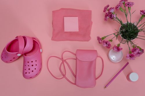 Free Flat lay of pink items including crocs, bag, flowers on a pastel surface. Stock Photo