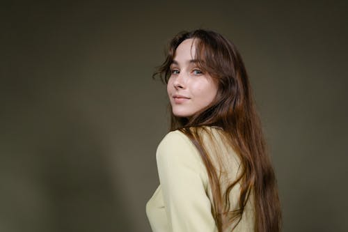 A Woman Wearing Beige Long Sleeve Shirt Looking Over her Shoulder