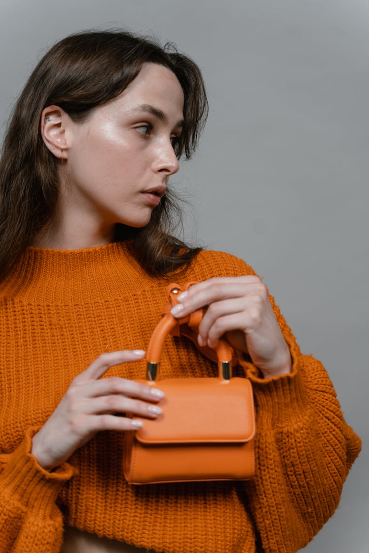 Woman In Orange Sweater Holding A Purse