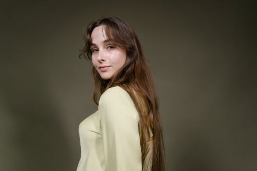 A Woman Wearing Beige Long Sleeve Shirt Looking Over her Shoulder
