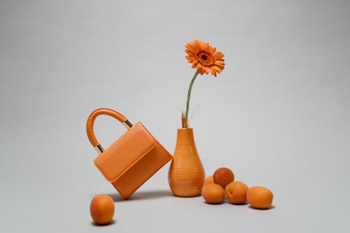 Orange Bag leaning on an Orange Vase