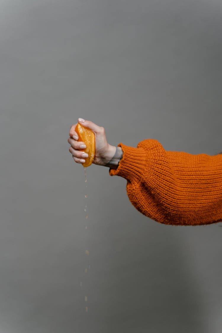 A Person Squeezing An Orange 