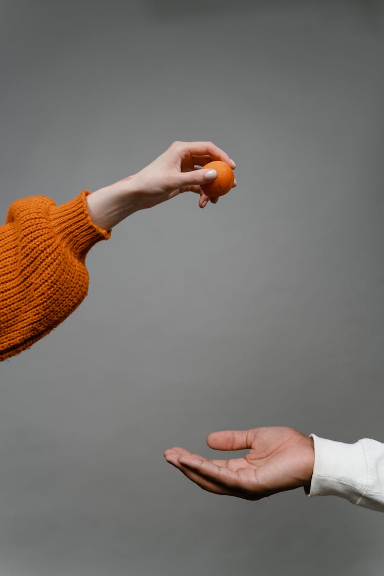 A Person About To Drop A Ball To Another Person's Hand