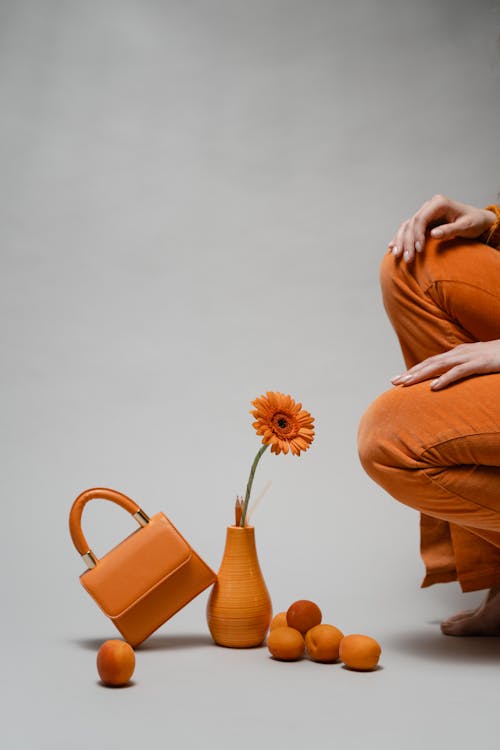 Free A Woman in Orange Pants Sitting Near Orange Items Stock Photo