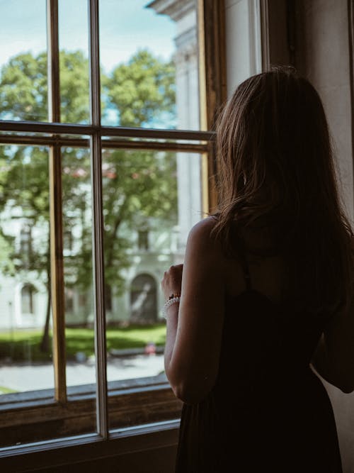 Free Woman Standing Beside a Glass Window Stock Photo