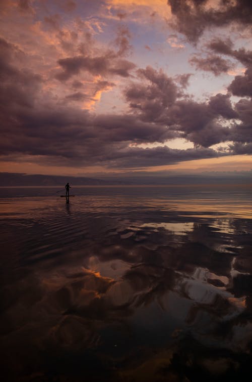 Silhouette of Boatman Paddling on Sea at Sunset