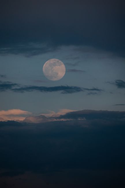 A calming full moon against a cloudy sky at dusk, capturing the beauty of lunar illumination.