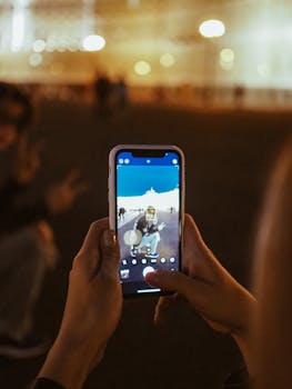 A person captures a playful scene outdoors at night using a smartphone camera.
