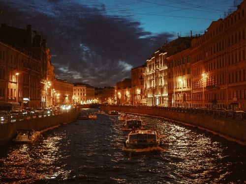 Free Romantic city canal scene at dusk with boats and illuminated buildings. Stock Photo