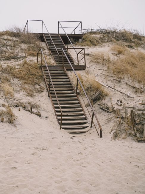A metal staircase leads through sandy dunes, offering a rustic path to the top. Perfect for coastal adventure themes.