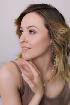 Elegant portrait of a smiling caucasian woman with short brown hair, light toned makeup, and a subtle necklace.