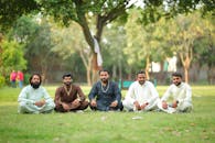 Group of People Sitting on Green Grass