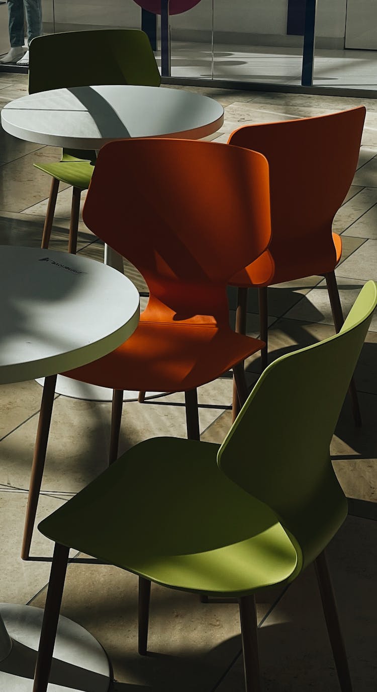 Orange And Green Chairs Near Round Tables