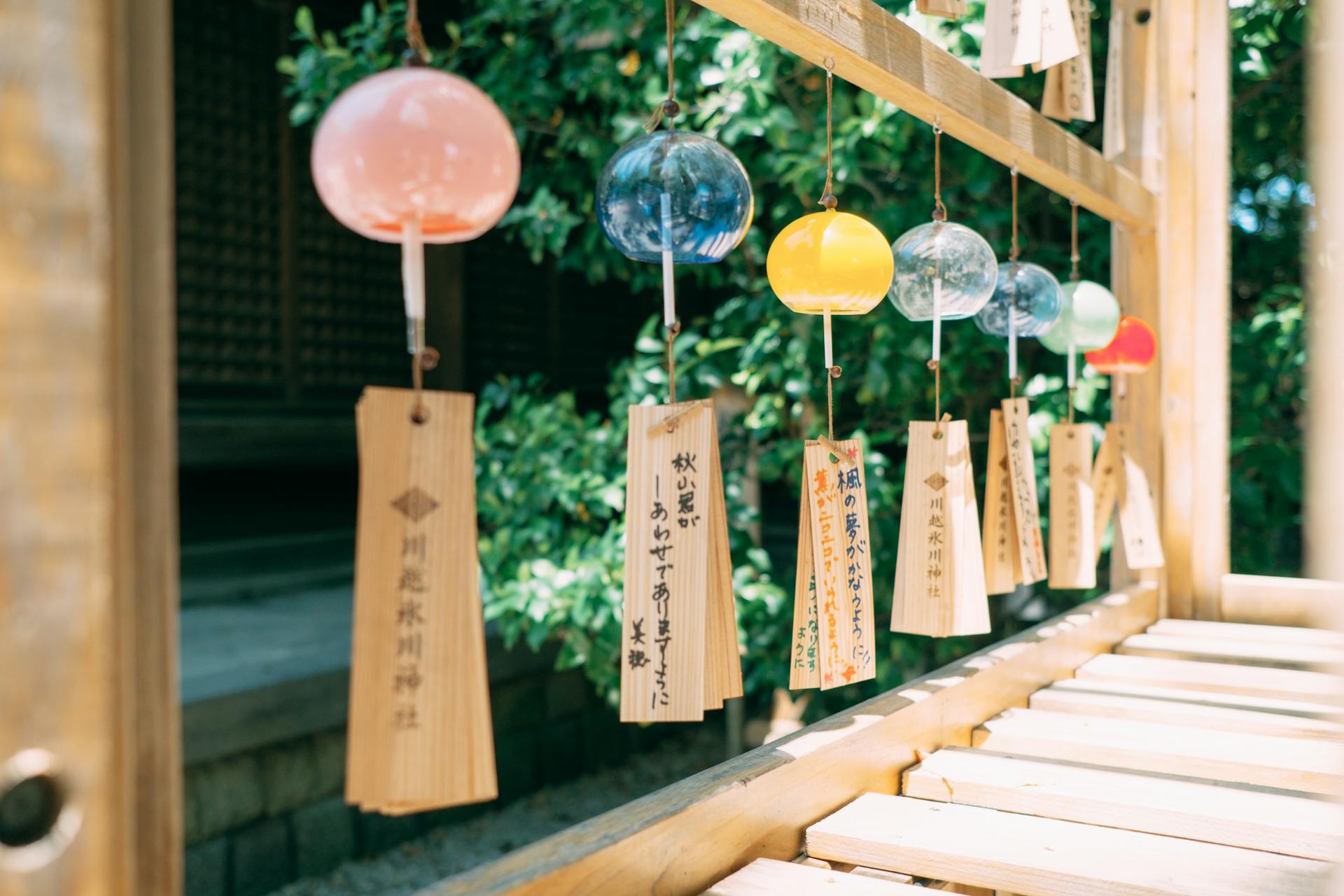 Vibrant Japanese wind chimes hanging in a tranquil garden setting, showcasing cultural artistry.