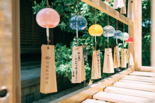 Free Vibrant Japanese wind chimes hanging in a tranquil garden setting, showcasing cultural artistry. Stock Photo