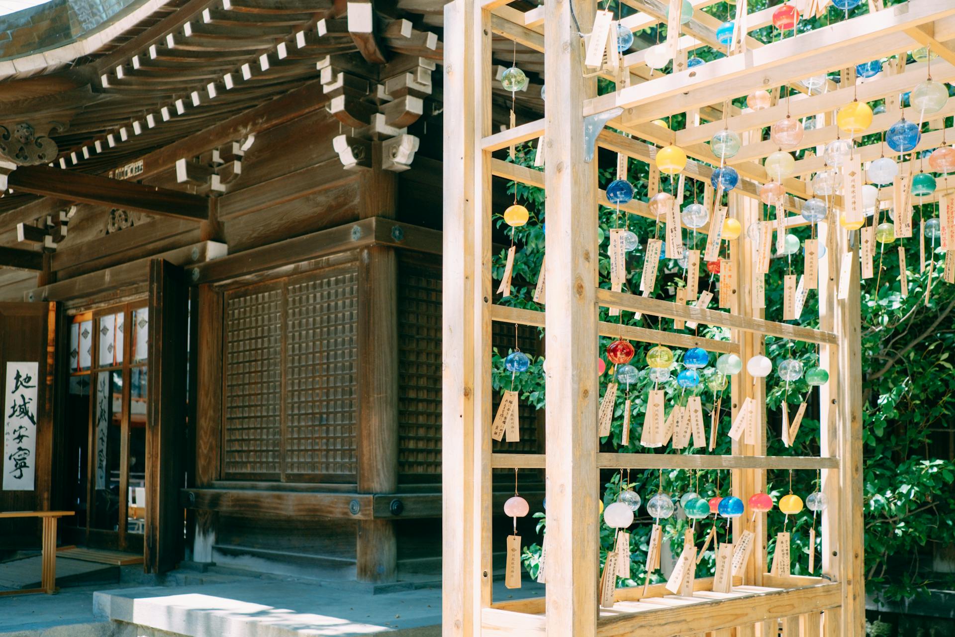 Beautiful Japanese temple architecture with colorful hanging glass wind chimes in a serene setting.