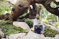Man Wearing White Shirt Sitting on Gray Rock