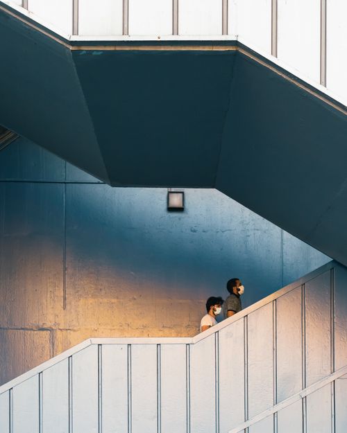 Free Two people walking up an urban staircase, showcasing modern city life. Stock Photo