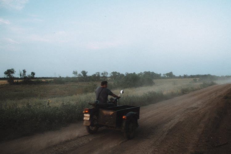 Man Riding A Tricycle On Dirt Road