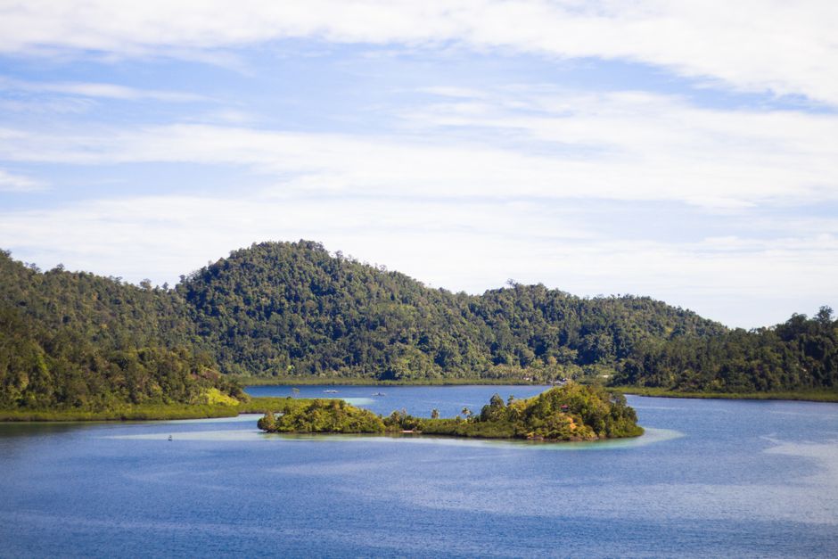 Serene island and hills surrounded by clear blue waters in West Sumatra, Indonesia.
