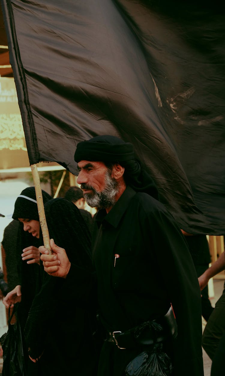 Man And Woman Wearing All Black Holding A Black Flag 