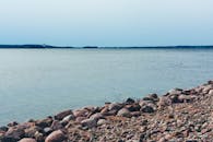 在晴朗的天空下，鹅卵石遍布的海岸与广阔的湖泊构成了一幅宁静的景象