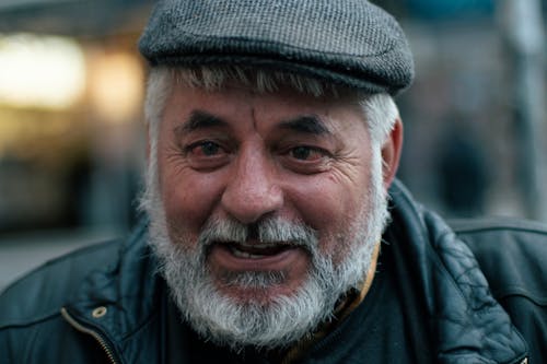 Man Wearing Black Jacket and Flat Cap Smiling