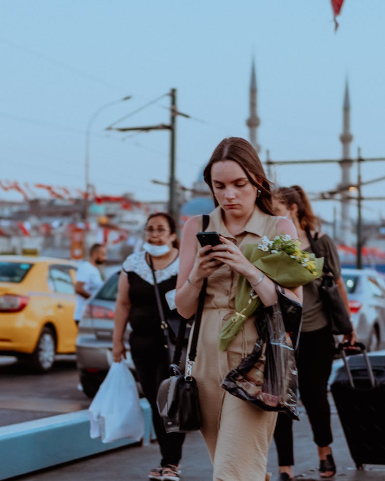 A Young Woman Using Her Phone While Walking In The Street