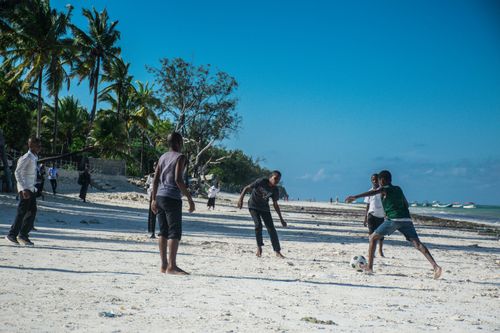 Free Group of boys enjoying a lively soccer game on a sunny Zanzibar beach. Stock Photo