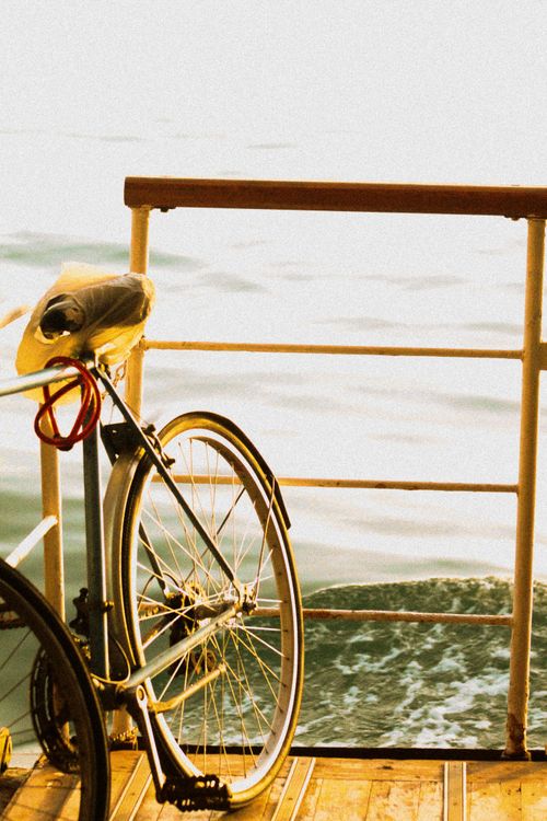 Free Vintage bicycle locked on a ferry railing with serene ocean view during sunset, emphasizing travel and leisure. Stock Photo