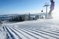 雪坡上，滑雪者在冬季的晴朗天空下乘缆车